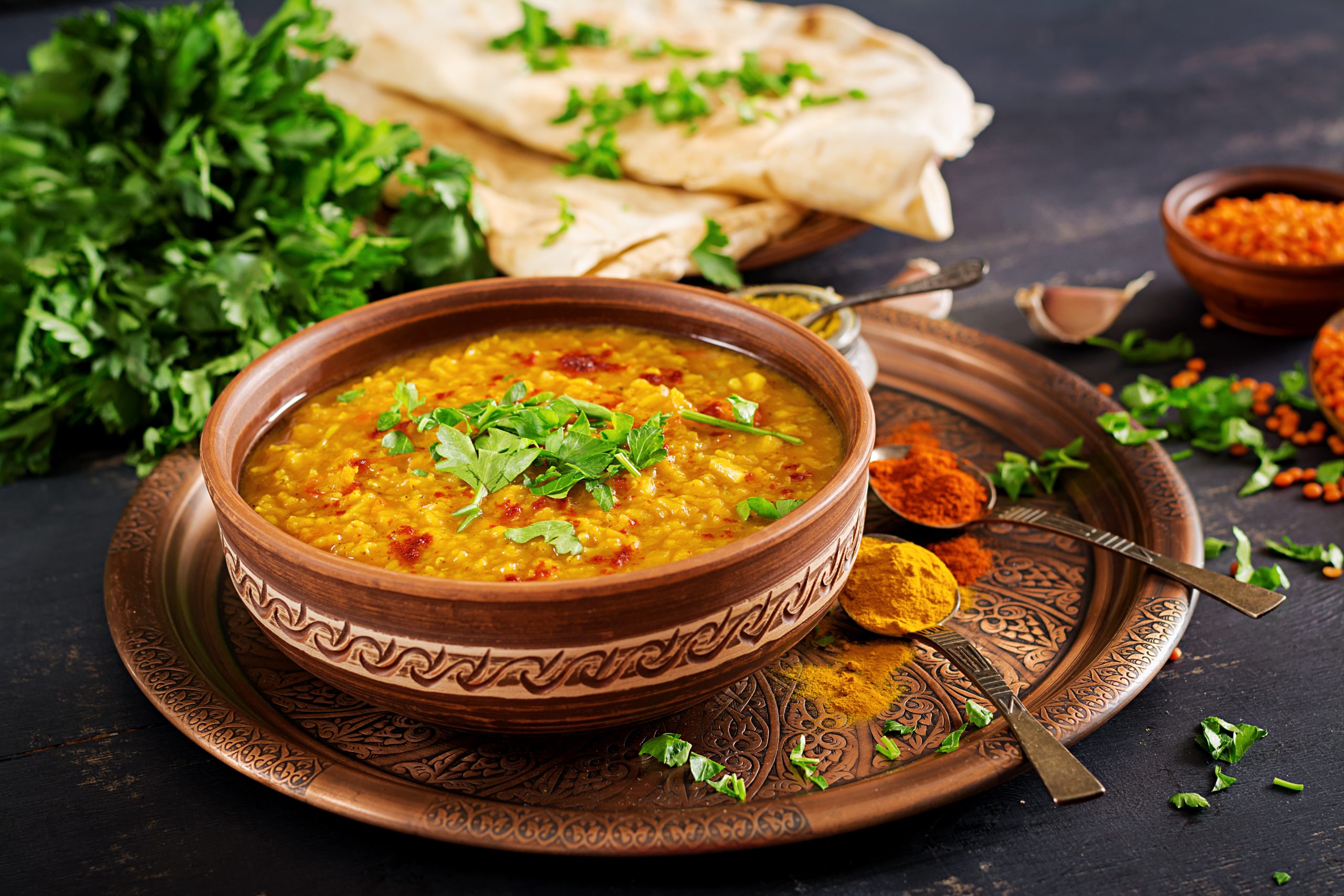 Indian dal. Traditional Indian soup lentils.  Indian Dhal spicy curry in bowl, spices, herbs, rustic black wooden background. Authentic Indian dish. Overhead